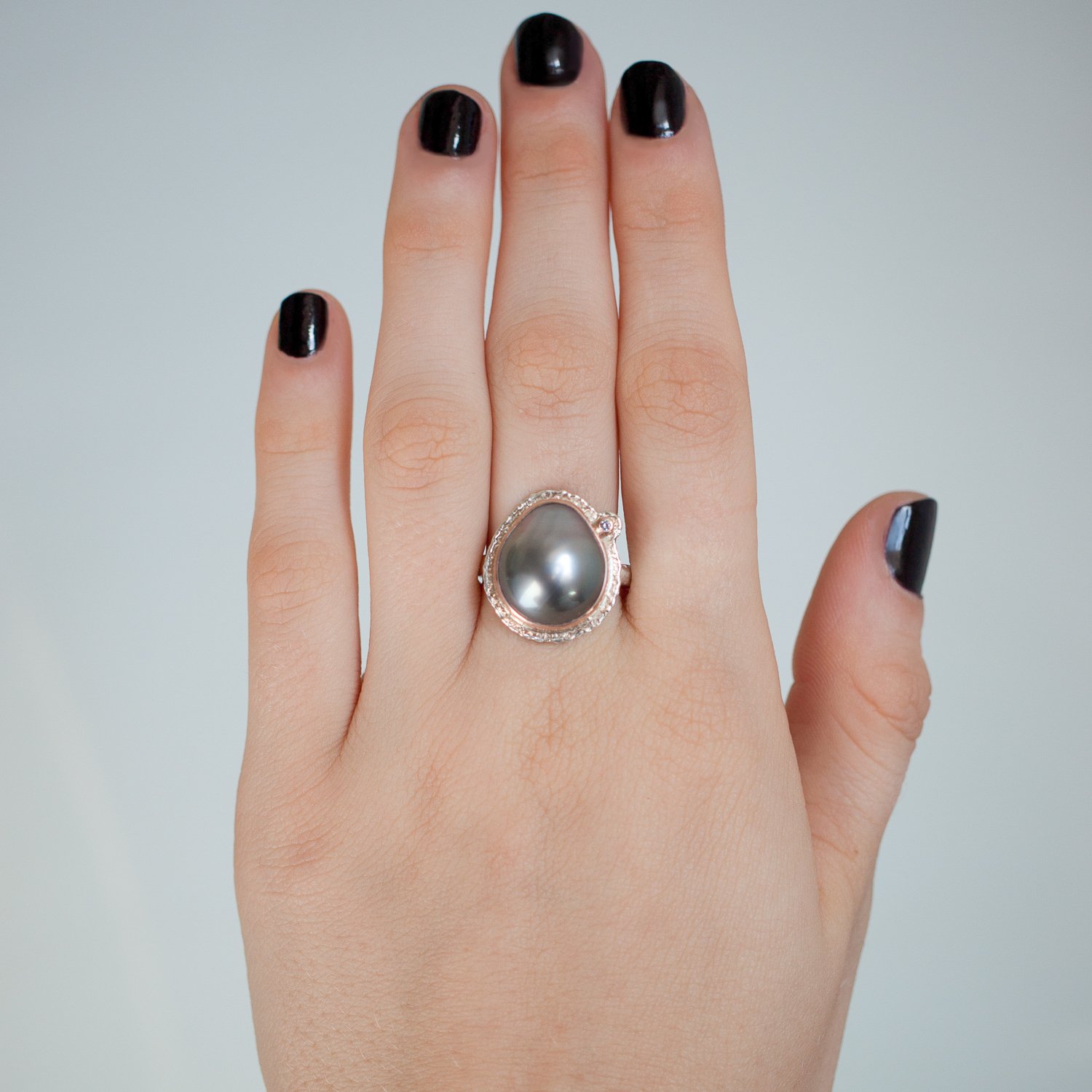 Jamie Joseph: SS and 14K rose gold ring with vertical asymmetrical Tahitian pearl and .025ct satellite diamond on lava platform and textured band size 7.5 5/8x1/2