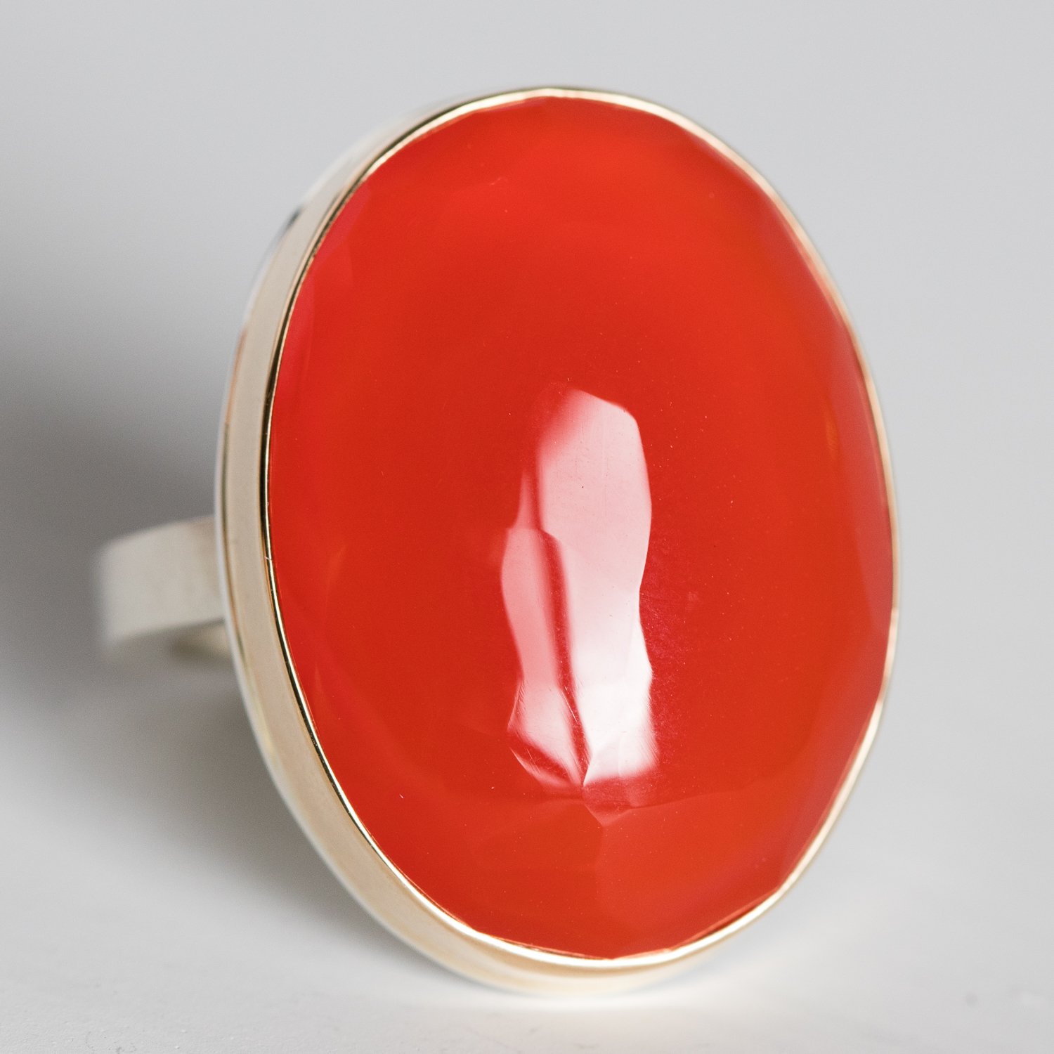 Jamie Joseph: 14K gold and sterling silver ring with vertical oval hand faceted carnelian on X band Size 7.5