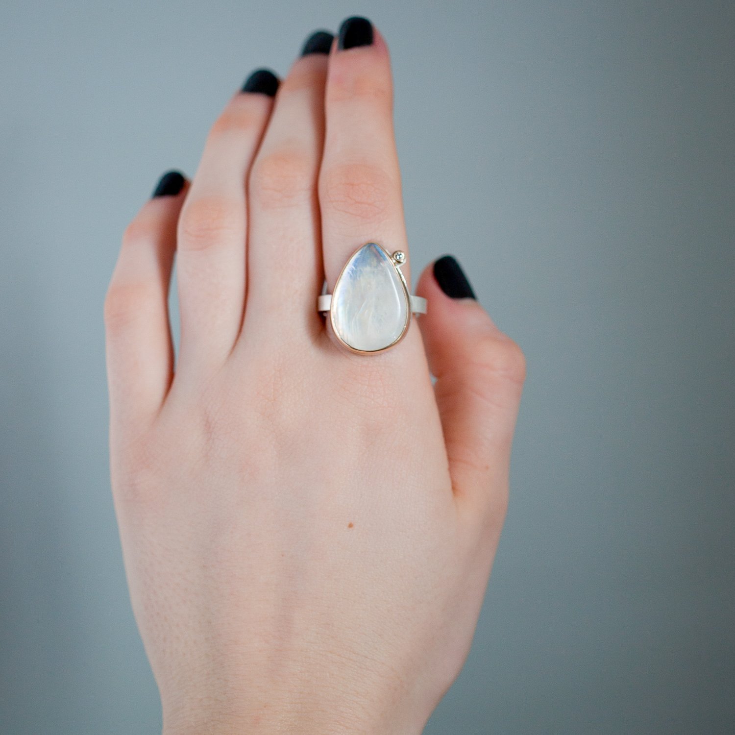 Jamie Joseph: 14K gold and sterling silver ring with vertical teardrop smooth white rainbow moonstone and .03ct satellite diamond on X band Size 7.5