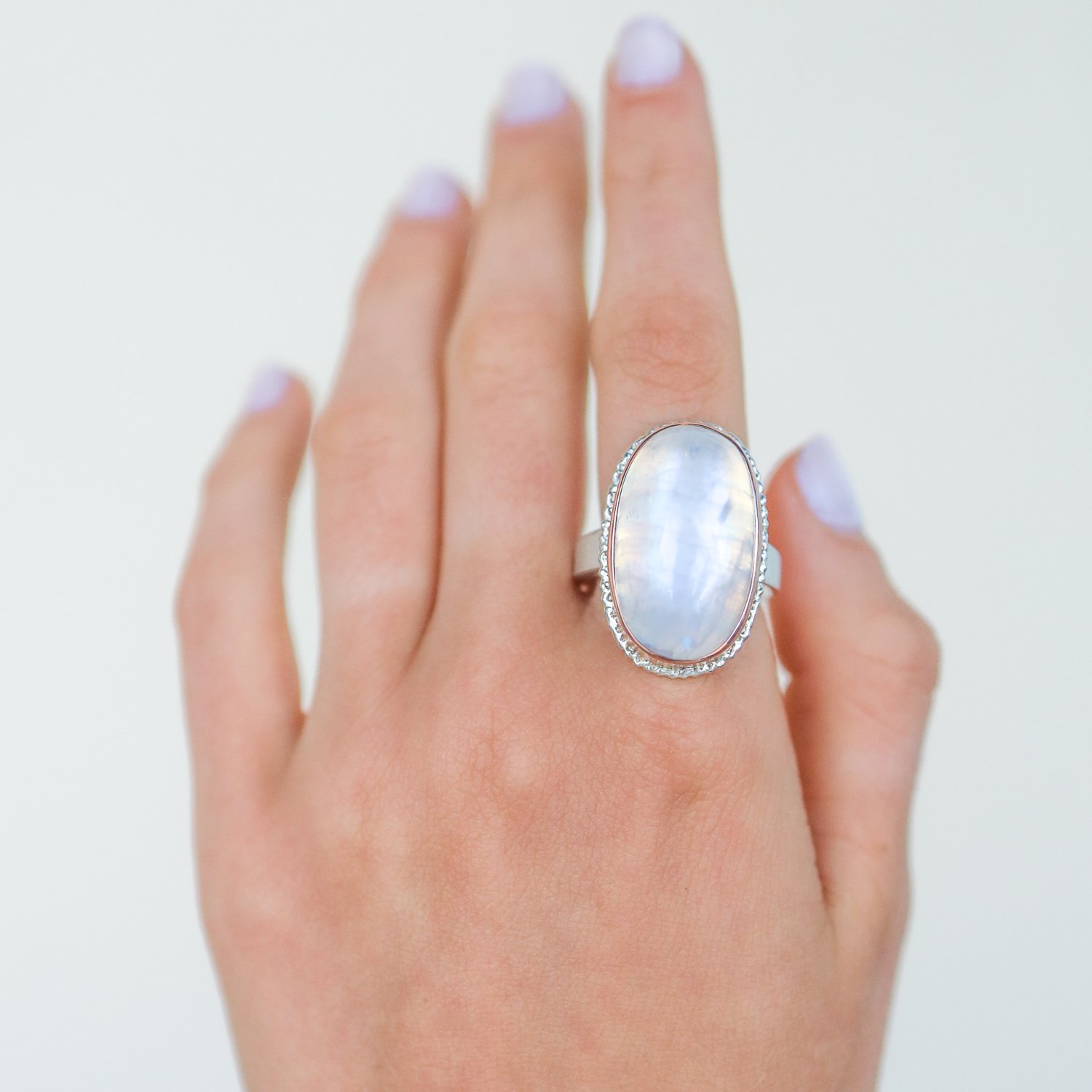 Jamie Joseph: Sterling silver and 14K rose gold ring with vertical oval smooth white rainbow moonstone on lava platform and tapered X band