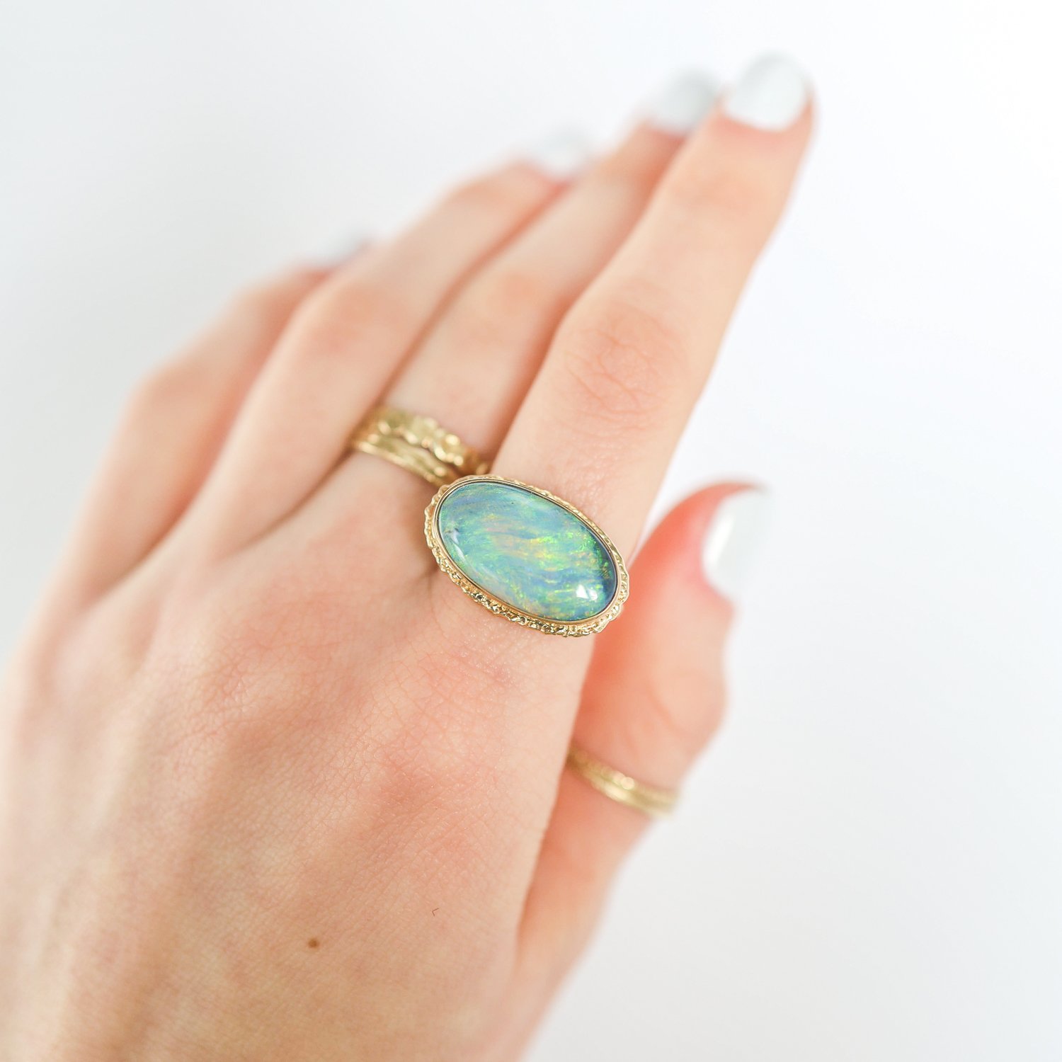 Jamie Joseph: Ring, Oval, 14K gold bezel set Australian black opal on ruffled platform, 14K gold sand band, Stone measures 7/16 x 3/4, Currently available in size 7