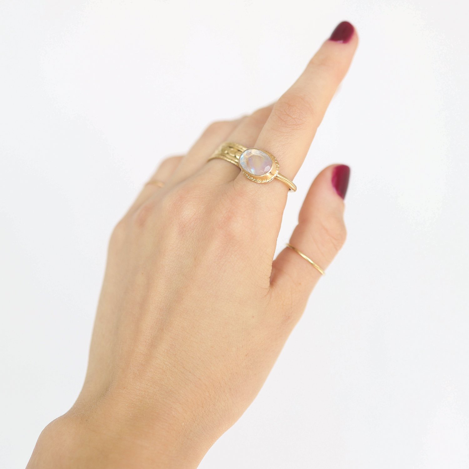 Jamie Joseph: Ring, Small oval table up, 14K gold bezel set white rainbow moonstone on open back ruffled platform, 14K dent band, Stone measures 5/16 x 1/2, Currently available in size 7 1/2