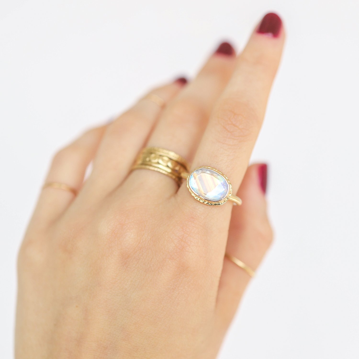 Jamie Joseph: Ring, Small oval table up, 14K gold bezel set white rainbow moonstone on open back ruffled platform, 14K dent band, Stone measures 5/16 x 1/2, Currently available in size 7 1/2