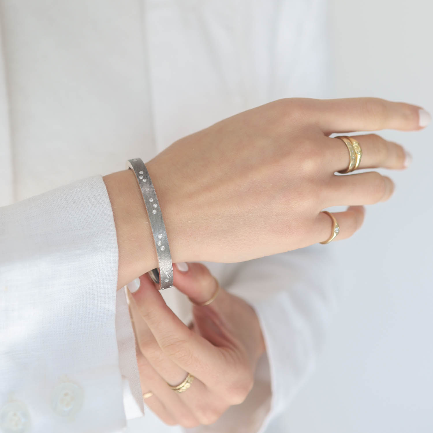 Rene Escobar: Bangle, MARU, 6mm in width, Oxidized sterling silver front & back, FIVE diamond clusters Diamonds .38, Size medium.