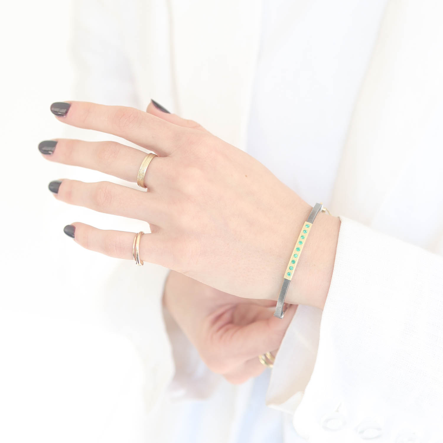 Rene Escobar: 2.5MM. SS hinged bangle featuring an 18k YG push button style clasp set with 0.35CT weight of EME diamonds.