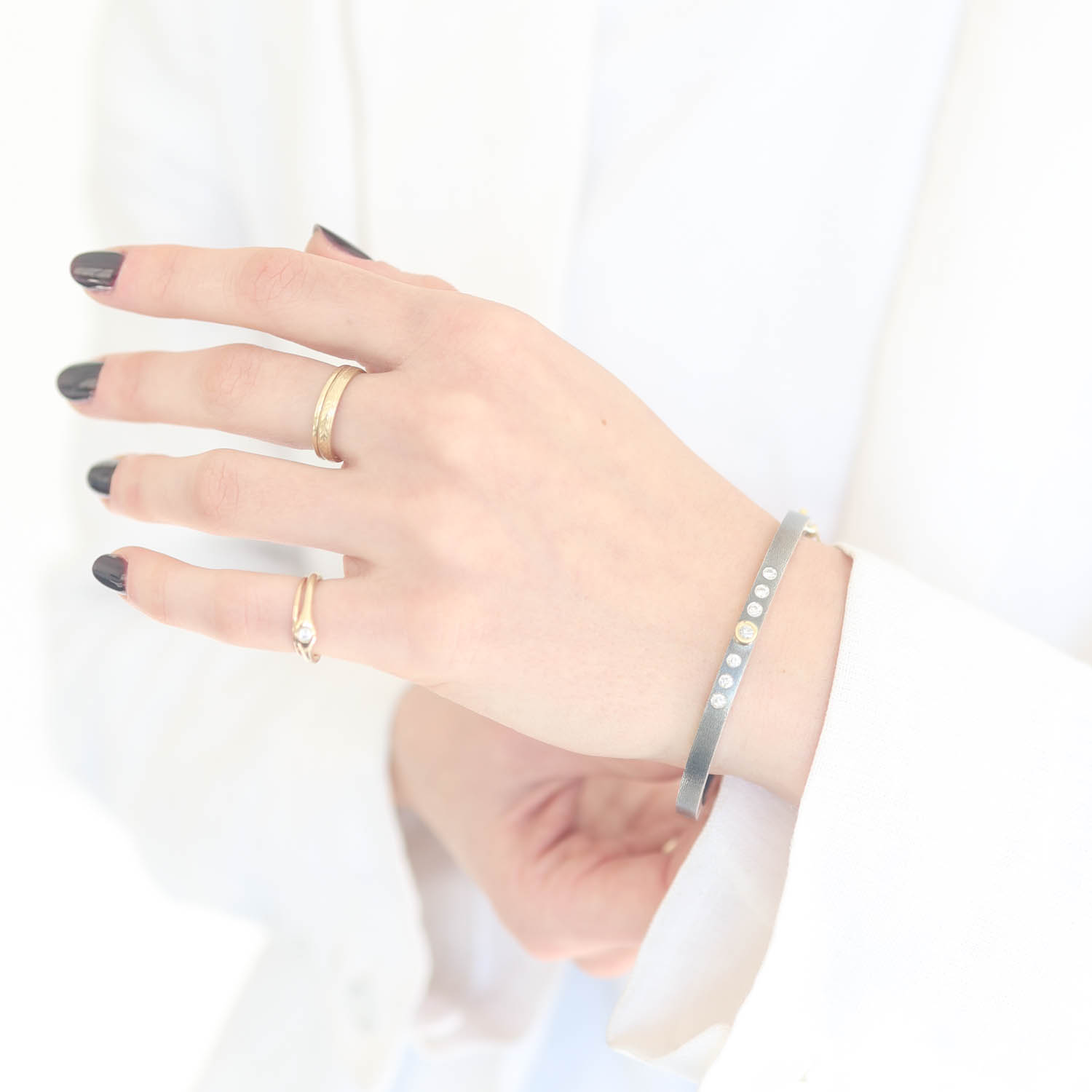 Rene Escobar Trunk Show:28 0.38CT 4MM. SS hinged bangle featuring an 18k YG push button style clasp and 7 18k YG bezels set with 0.38CT in WH diamonds.